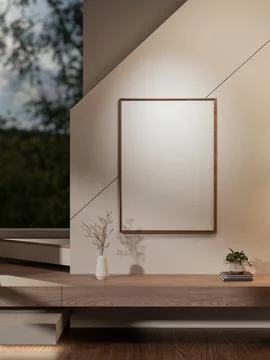 Blank frame hanging over a vase and potted plant on books aside wooden stai.. Ilustración de archivo