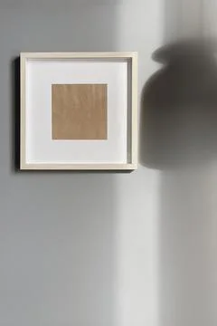 Blank frame with mockup copy space on grey wall with lamp sunlight shadows. A Fotos de archivo