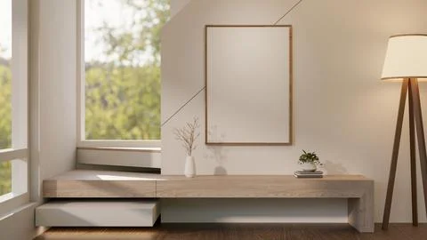 Blank frame over a vase and plant on books aside wooden staircase and sunsh.. Ilustración de archivo