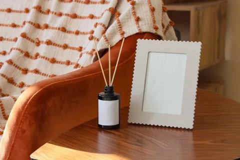 Blank frame with reed diffuser on table in living room Stock Photos