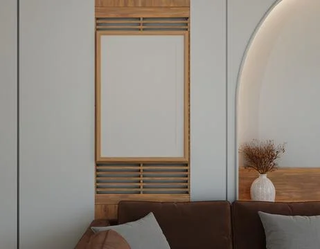 Blank framed art piece on light gray wall, wooden accents, brown couch Stock Photos