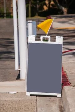 Blank gray sandwich type chalk board on a street with a yellow flag to draw a Stock Photos
