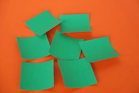 Blank green sticky notes scattered on vibrant orange background. Creative office Stockfoto's