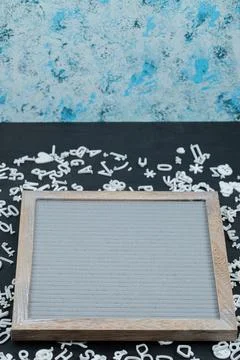 Blank grey frame with white pins and letter symbols around Stock Photos