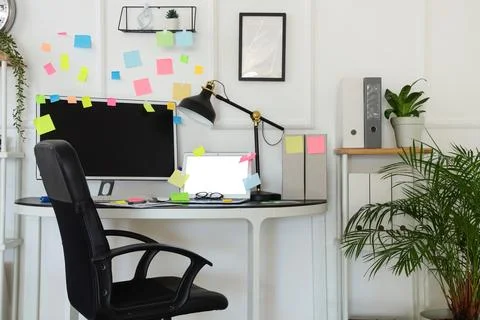 Blank laptop with computer and sticky notes on desk in light office Stock Photos
