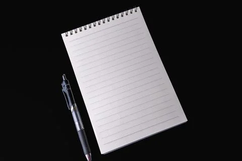 Blank lined spiral notepad and pen placed on a black background Stock Photos