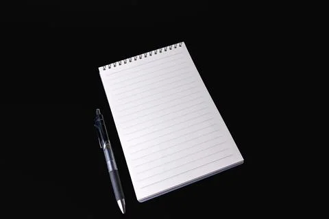 Blank lined spiral notepad and pen placed on a black background Stock Photos