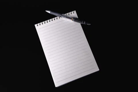 Blank lined spiral notepad and pen placed on a black background Stock Photos