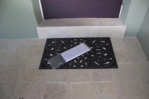 Blank newspaper in wrapper on doormat at front door Stock Photos