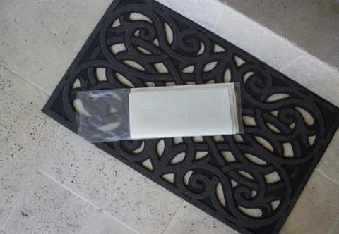 Blank newspaper in wrapper on doormat at front door Stock Photos