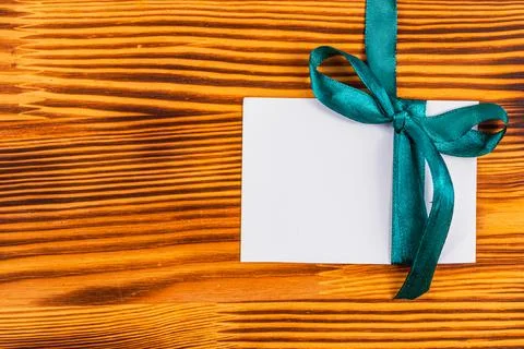 Blank note with green ribbon on right on wooden board, concept Foto stock