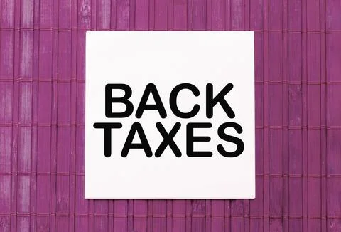 Blank note pad with text BACK TAXES on blue wooden background Foto stock