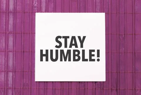 Blank note pad with text stay humble on blue wooden background Stock Photos