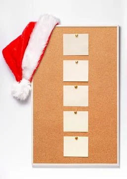 Blank note sheets are pinned to the board. Santa's hat on a cork board. Stock Photos