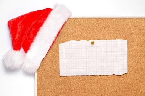 Blank note sheets are pinned to the board. Santa's hat on a cork board. Stock-Fotos