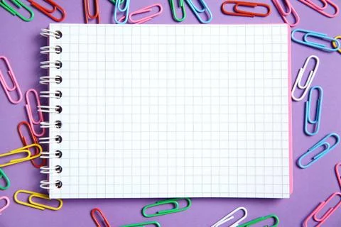 Blank notebook and paper clips on purple background, flat lay. Space for text Stock Photos