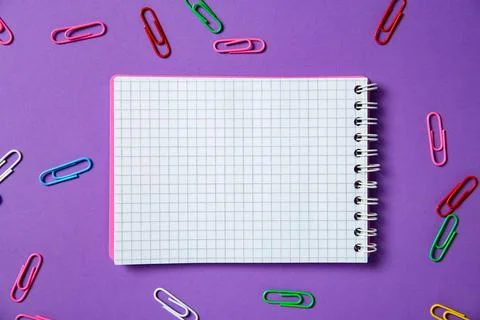 Blank notebook and paper clips on purple background, flat lay. Space for text Stock Photos