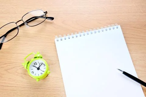 Blank notebook and pen with clock on a desk Foto stock