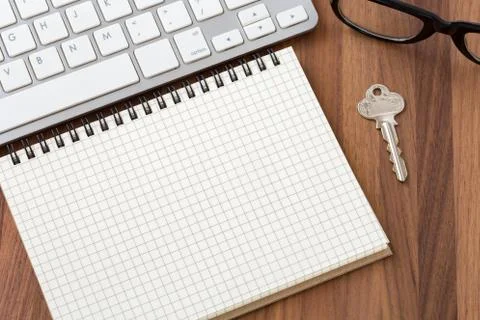Blank notebook with computer and key on wooden table Stock Photos