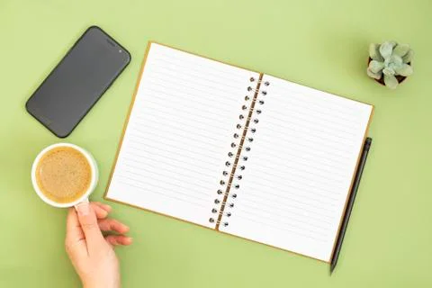 Blank notebook with empty page, pencil and hand holding a coffee cup. Table t Stock Photos
