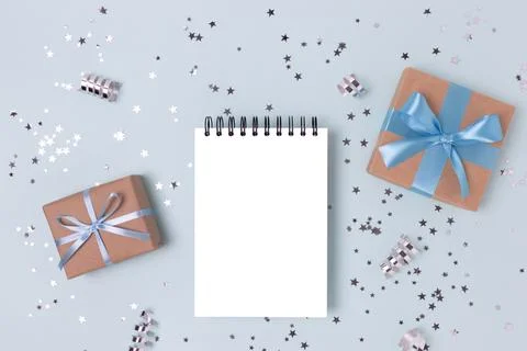 Blank notebook mockup, gift boxes and silver confetti. Stock Photos