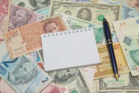 Blank notebook page with pen on background from world currencies Stock Photos