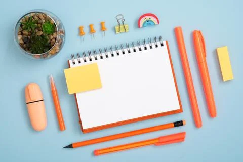 Blank notebook page for your text with orange pen and pencil on blue back Stock Photos