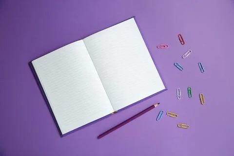 Blank notebook, paper clips and pencil on purple background, flat lay. Spac.. Stock Photos