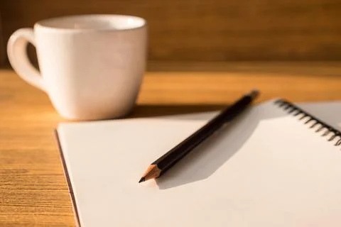 Blank notebook with pencil and coffee cup on wooden table background. Selec.. Stock Photos