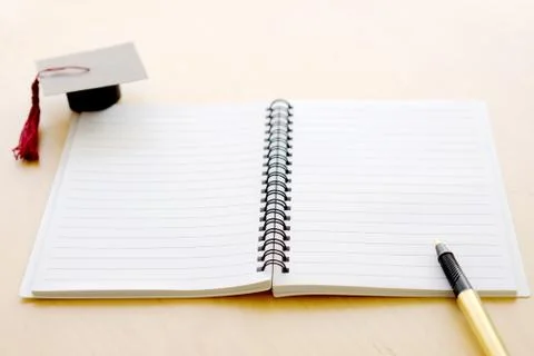 Blank notebook on the table and graduation cap Stock Photos
