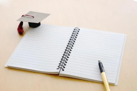 Blank notebook on the table and graduation cap Foto stock