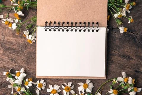Blank notebook with white flower and bas ket of flower on vintage wooden table V Stock Photos