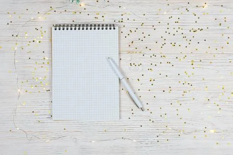 Blank notebook with a white pen on a white table with gold sparkles, stars Stock Photos