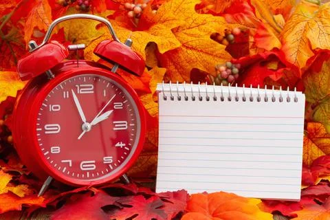 Blank notepad with an alarm clock and fall leaves Stock Photos