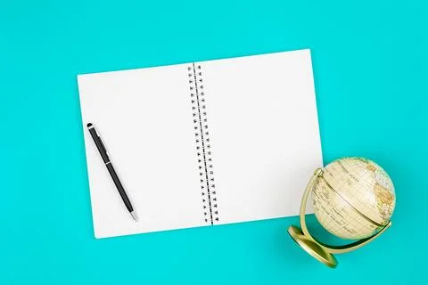 Blank notepad and globe on a blue background, flat lay. Stock Photos