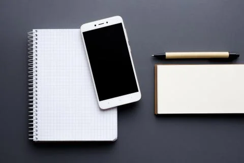 Blank notepad and notebook with smartphone and pen over gray background Stock Photos