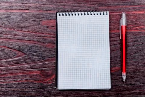 A blank notepad with a ballpoint pen to the side and placed on a mahogany woo Stock Photos