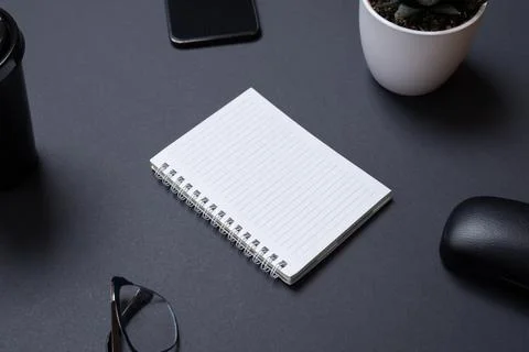 Blank notepad on black work desk witc copy space. Surounded by office supplie Stock Photos