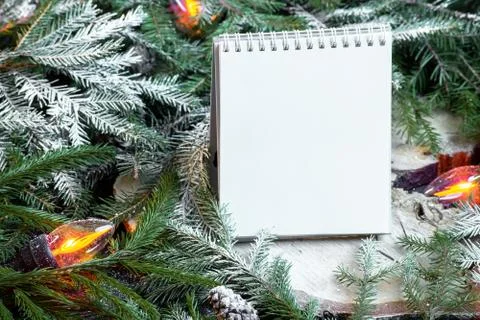 Blank notepad on christmas tree branches, new year decoration and garland. Stock Photos