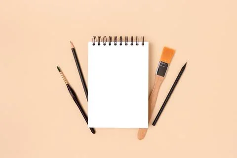 Blank notepad mockup and tools for painting on a beige background. Stock Photos