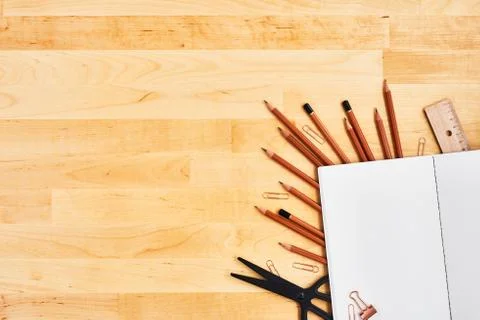 Blank notepad over school and office supplies on yellow wooden table. Stock Photos