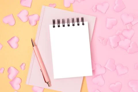 Blank notepad, pen and textile hearts confetti on a pink background. Stock Photos