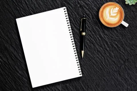 Blank notepad pen on black stone office desk with coffee cup ,top view Stock Photos