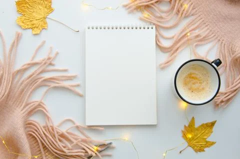 Blank notepad on the white table with knitted pink scarf, coffee mug and autumn Stock Photos