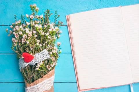 Blank open notebook and white flowers. Flat lay of a woman desk. Stock Photos