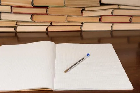 Blank open notepad with pen on the table with books background Stock Photos