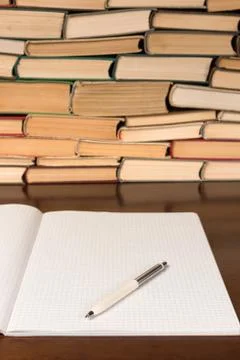 Blank open notepad with pen on the table with books background Foto stock