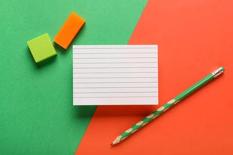 Blank paper card with different rubber erasers and pencil on color background Stock Photos