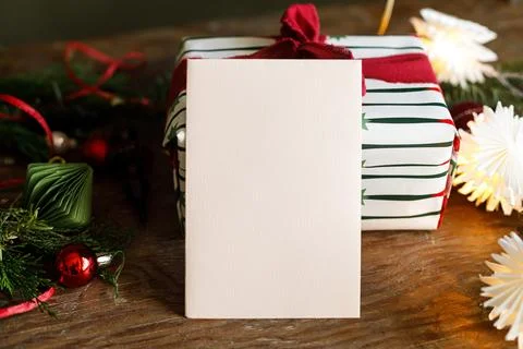 Blank paper card mockup vertically in front of wrapped gift box. Christmas .. Foto stock