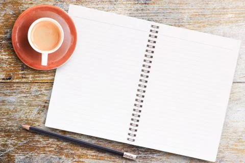 Blank paper notebook with pencil and cup of coffee on wooden table